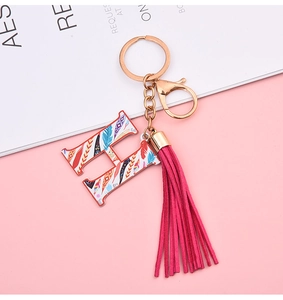 Detail of letter H keychain with colorful feather pattern and magenta leather tassel
