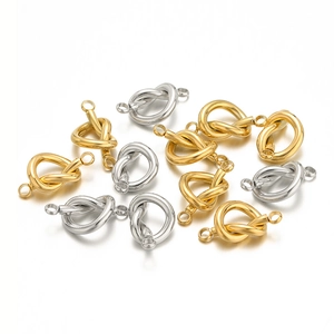 Macro shot of gold and silver knot-shaped jewelry connectors on a white background