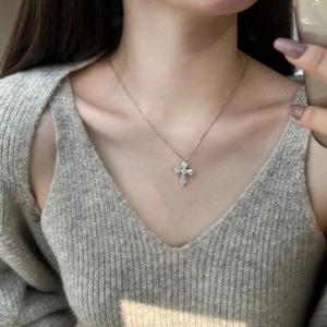Detail of S925 sterling silver cross necklace with cubic zirconia on a model's neck