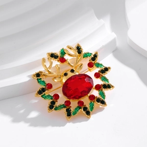 Elegant Christmas reindeer brooch with red crystal and green enamel wreath on white stand