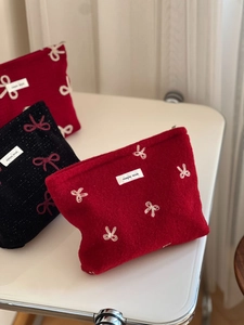Detail of red and black velvet cosmetic bags featuring sequined bow embroidery patterns