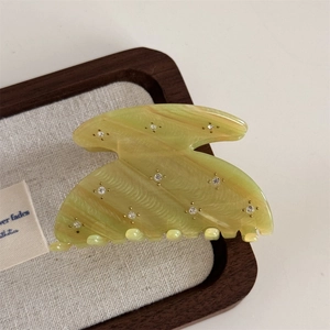 Macro detail of star rhinestone accents on acetate hair claw clip with glossy finish