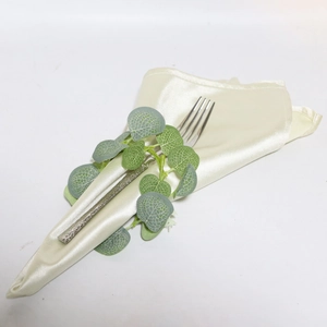 Detail of cream silk napkin and hammered silver fork for elegant Easter table setting