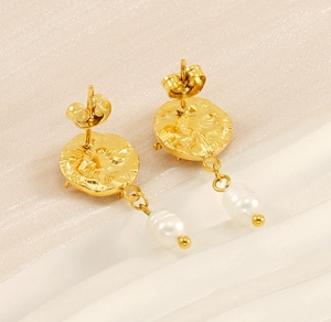 Detail of vintage gold pearl earrings with hammered metal texture and star design