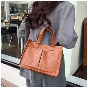 Detail of vintage brown textured PU leather tote bag with large front pockets on a model