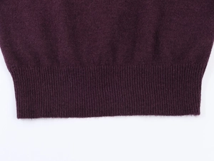 Détail de pull en maille violet foncé avec ourlet côtelé et texture de laine fine