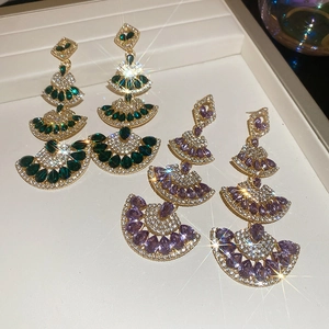 Detailed macro of tiered fan-shaped earrings with emerald and amethyst stones