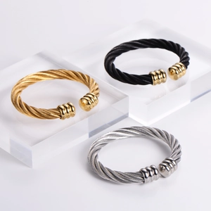 Three twisted cable cuff bracelets in gold, silver, and black finish with steel wire texture