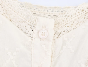 Détail du col en dentelle crème avec broderie délicate et un bouton rond élégant