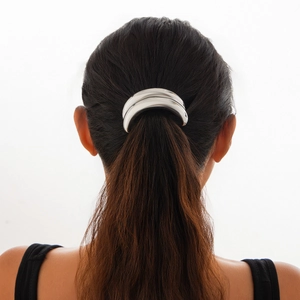 Detail of a silver metallic elastic hair cuff on a ponytail shown from a back view