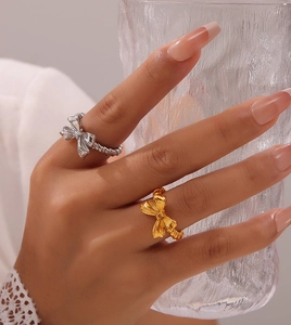 Dettaglio degli anelli a forma di fiocco oro e argento sulla mano della modella