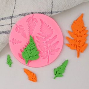 Pink silicone fern leaf mold with realistic green fondant leaf decorations for cake design