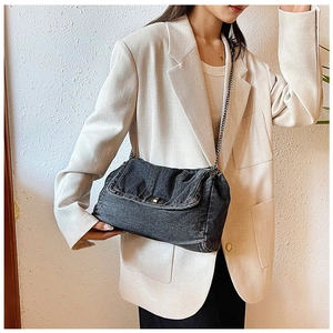 Detailed close-up of dark grey denim tote with silver chain strap and metal lock closure