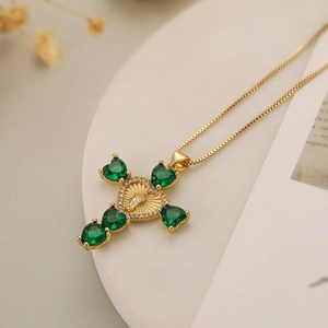 Detailed macro of 18K gold plated cross pendant with green heart stones and angel relief