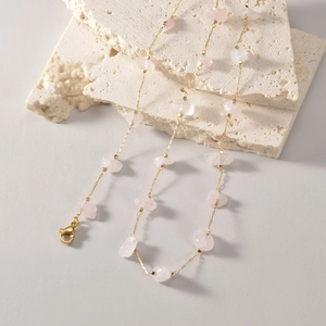 Detail of vintage bohemian gold chain with irregular pink stones on a stone display