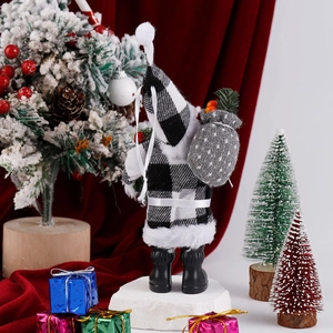 Detail of Santa Claus plush in black and white plaid clothes on a snowy stone base