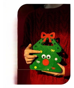Detail of handmade green felt Christmas tree gift bag with red bow and eye decorations
