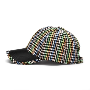 Close-up of colorful houndstooth fabric and black leather brim on a stylish baseball cap