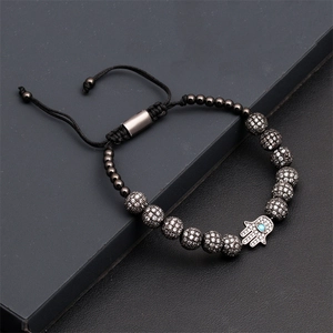 Détail de la main de fatma avec œil bleu sur bracelet tressé noir serti de zircons