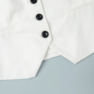 Detailed view of white woven vest with black buttons and symmetrical flat pockets