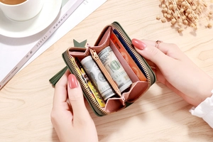 Detail of dark green accordion zip wallet with pink interior and gold zipper tassel