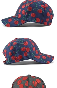 Close-up detail of stylish baseball cap featuring red cherry jacquard pattern on dark fabric