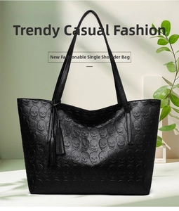 Detailed view of black tote bag with skull embossed texture and tassel accessory