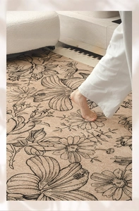 Detailed texture of soft velvet beige rug with black floral line art and model feet