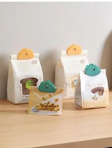 Cloud-shaped food clips in yellow and green sealing various bread and snack bags on wood