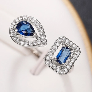 Close-up of silver ring with pear and emerald cut blue stones and zircon pavé