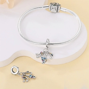 Detail of silver snake chain bracelet with music note and butterfly charms with zircons