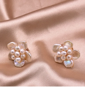 Macro view of gold flower earrings with baroque pearls on champagne silk fabric