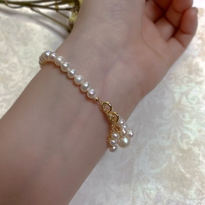 Detail of baroque pearl bracelet with gold clasp and elegant cluster pearl drop charm
