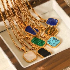 Detail of square gold pendants with various gemstones in a luxury wooden jewelry box