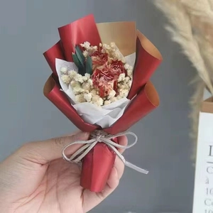 Close-up of a mini dried flower bouquet with red roses and baby's breath in hand