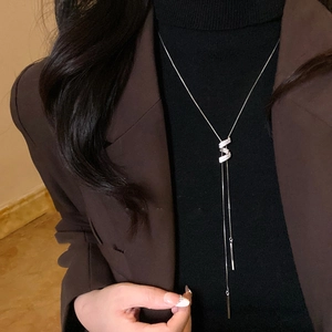 Dettaglio della collana con pendente in zircone argento indossata su un blazer marrone