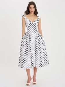 Vooraanzicht van een elegante witte jurk met zwarte stippen, V-hals en uitlopende rok