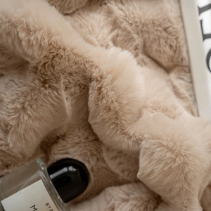 Macro shot of ultra-soft beige faux rabbit fur blanket with luxury texture and thick pile