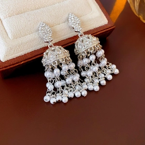 Macro detail of silver bell-shaped tassel earrings with rhinestones and white pearls
