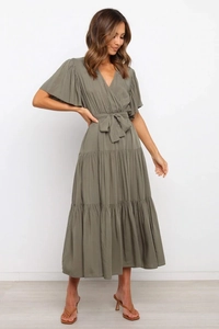 Detalle de vestido largo verde oliva con escote en V, mangas con volantes y falda de capas
