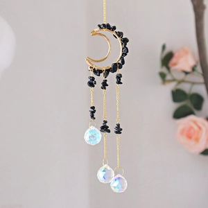 Detail of moon suncatcher with black gravel stones and faceted crystal prisms