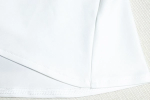 Detailed close-up of white A-line dress hem featuring premium twill fabric and fine stitching