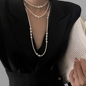 Elegance detail of multi-layered pearl necklace worn with a stylish black blazer suit