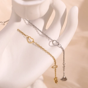 Detail of minimalist 14K gold and silver plated heart anklets on ceramic display