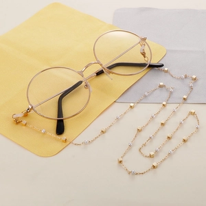 Golden titanium steel chain with pearls for glasses and masks on a textured background