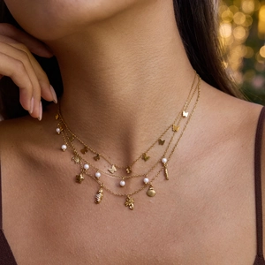 Close-up of triple-layered gold stainless steel necklace with butterfly and shell charms