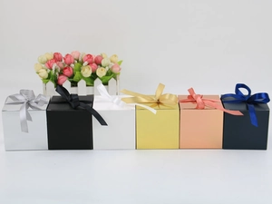 Row of small square gift boxes in metallic colors with matching silk ribbon bows