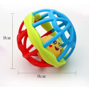 Détail d'une balle hochet colorée de 9cm pour bébé avec poignée souple et visage souriant