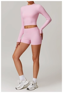 Vue latérale de l'ensemble de sport rose avec haut court à manches longues et short taille haute