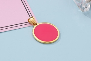 Detailed macro view of the gold oval pendant with vibrant pink enamel inlay